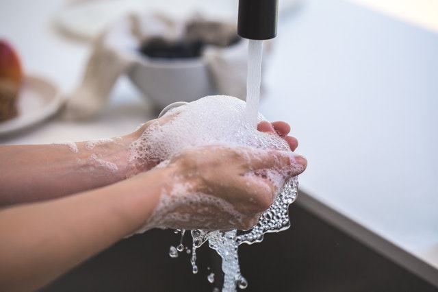 person washing hands in sink