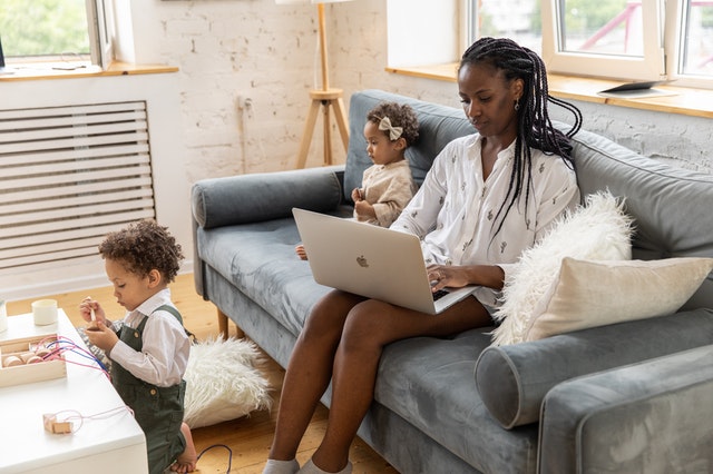 woman working from home on laptop with two kids in the "new normal"