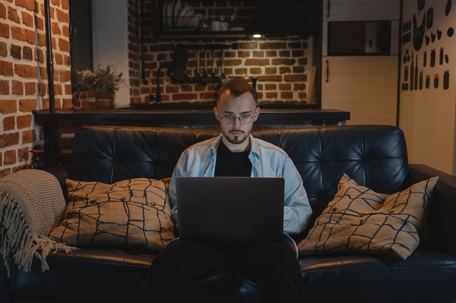 man working at computer on couch