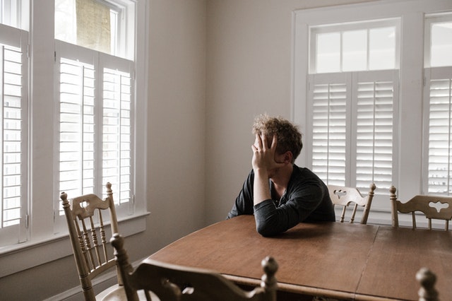 A man sitting at a table with his head in one hand
