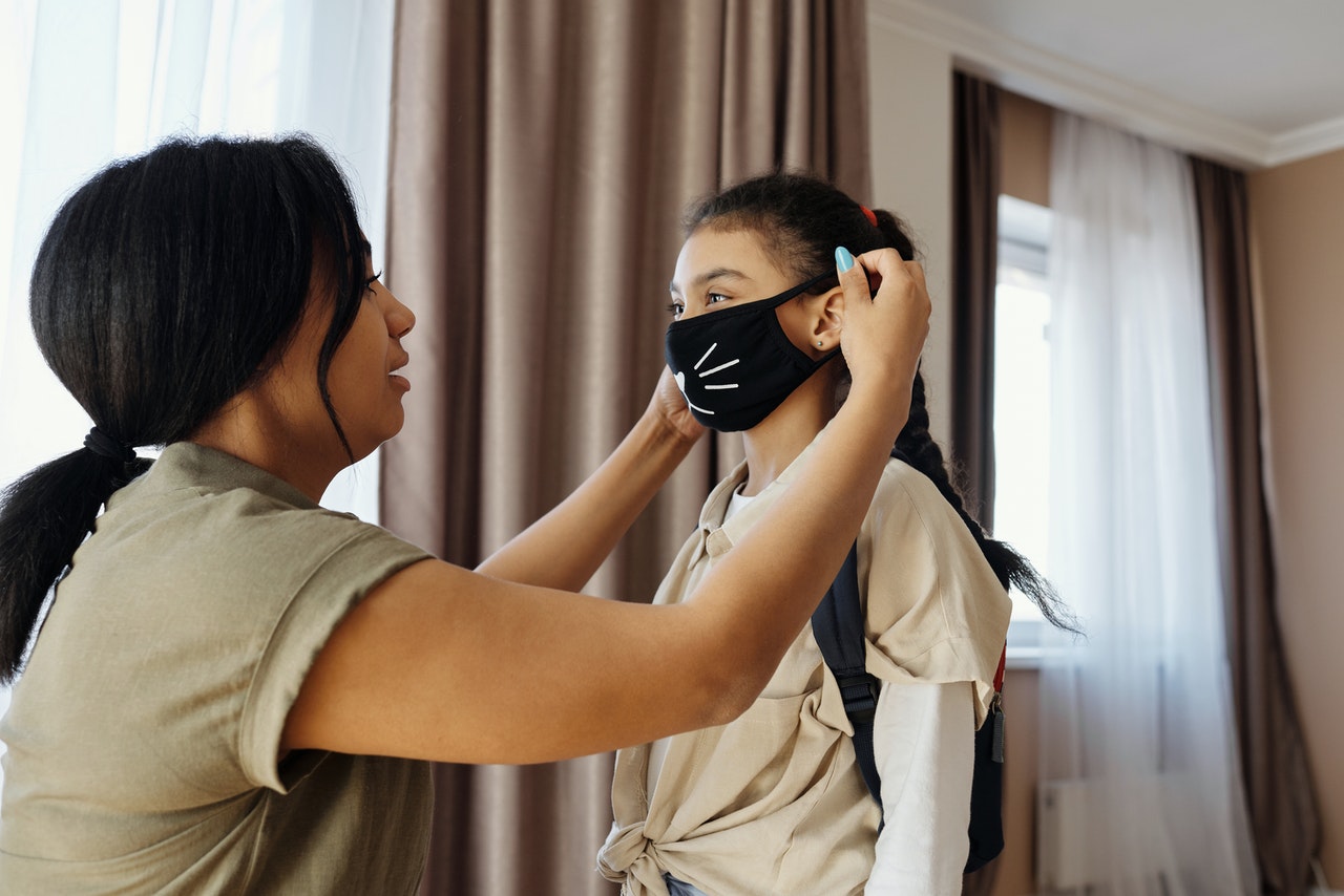 woman putting mask on daughter