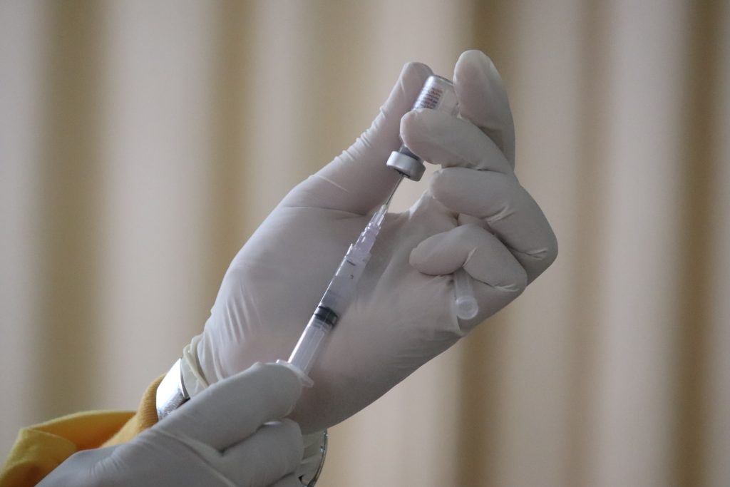 A vaccine being drawn out of a vial through a syringe