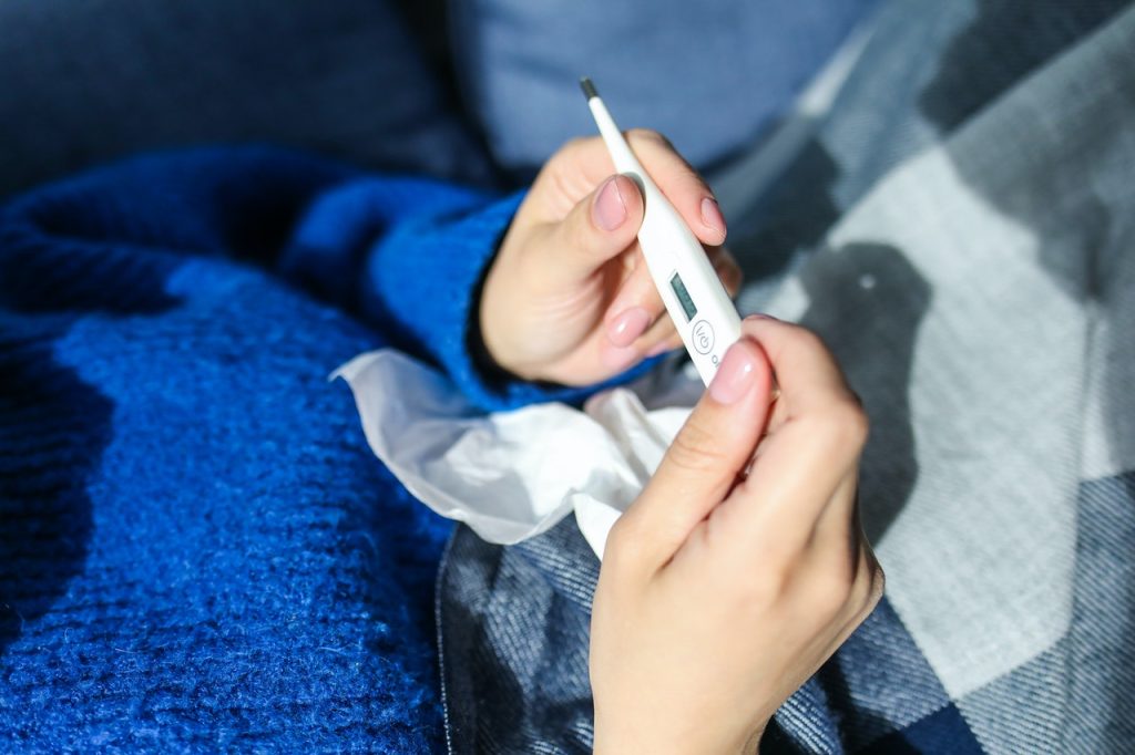 sick woman checking temperature with thermometer