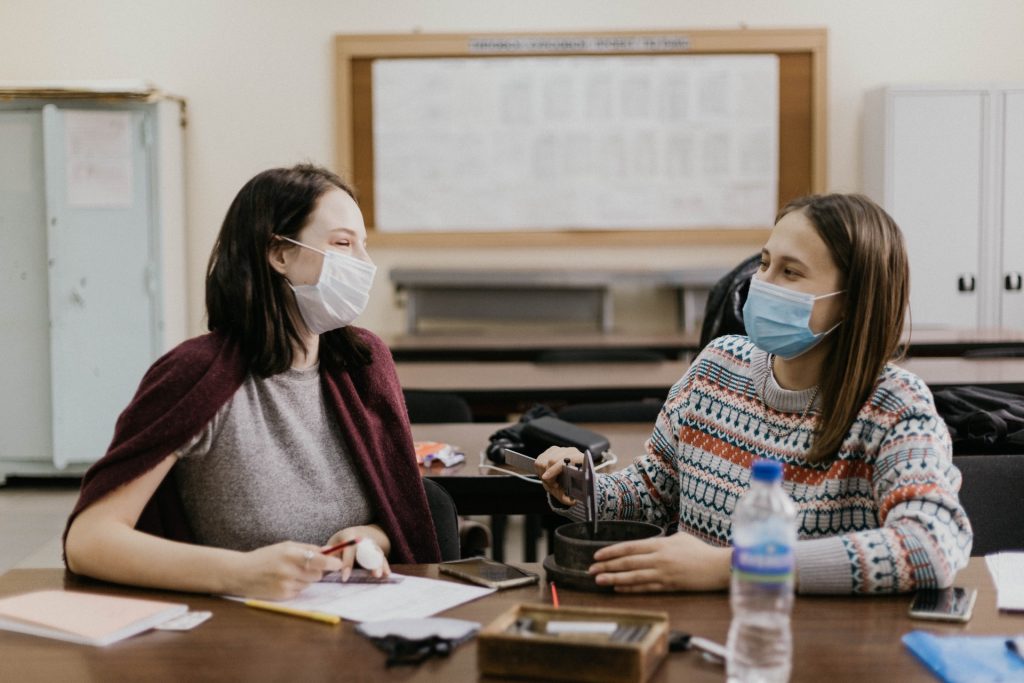 Two friends talking while wearing face masks