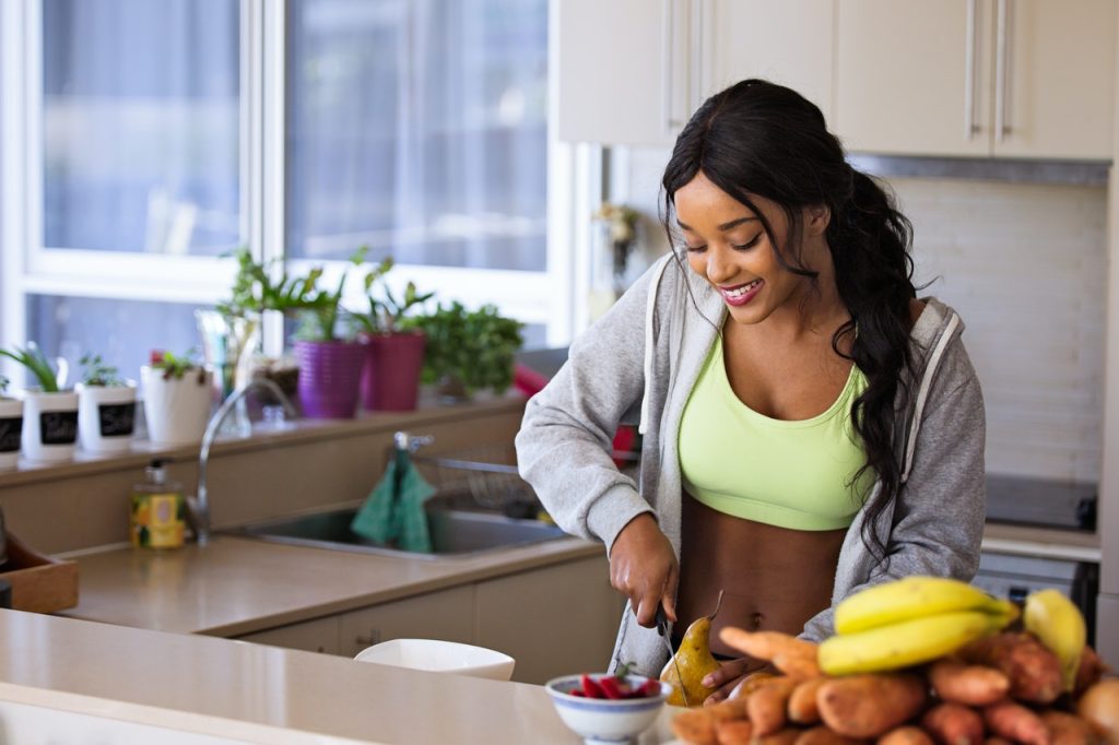 A woman wearing sportswear and slicing fruits in the kitchen