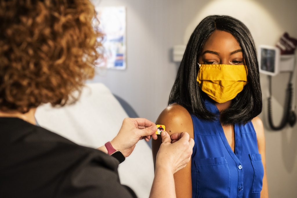 A woman wearing a face mask and receiving a vaccine