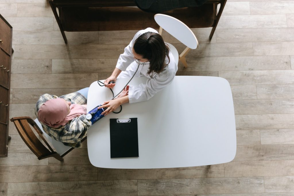 Doctor taking patient's blood pressure at table