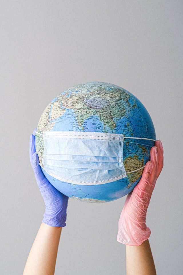 Gloved hands holding globe with face mask