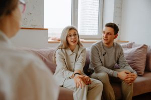 man and woman sitting on couch talking to therapist