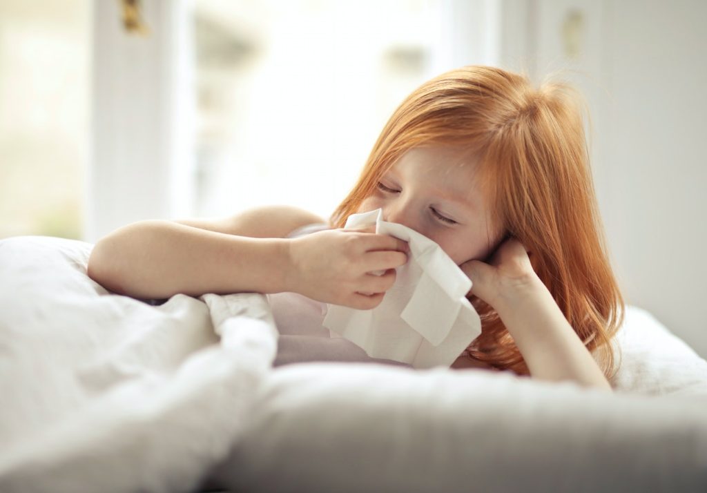 A child with allergies sneezing into a tissue