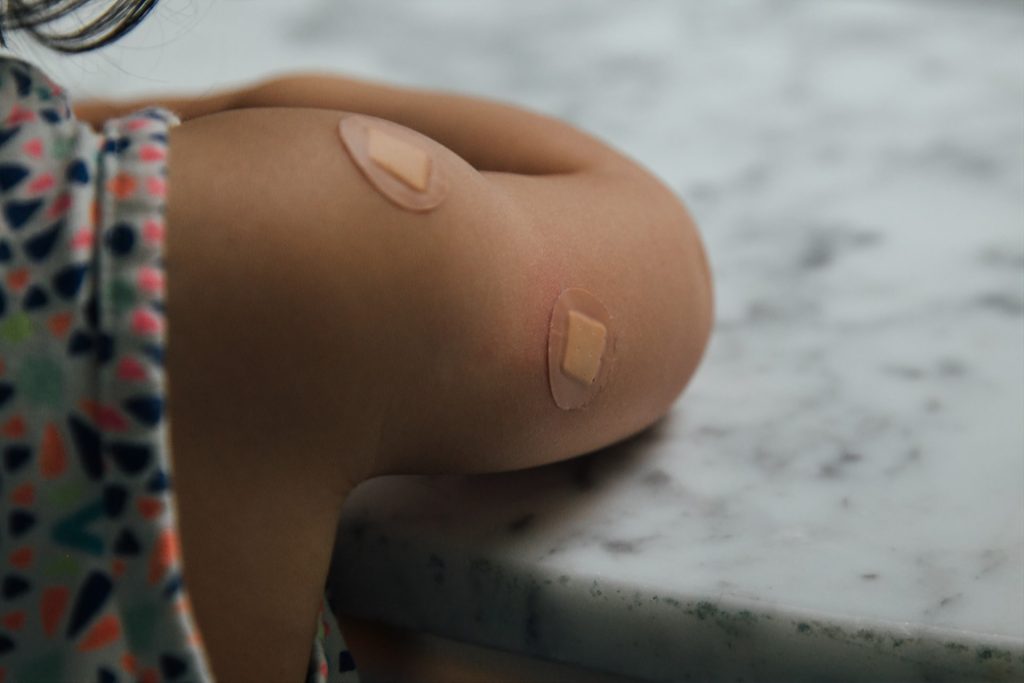 Child's arm with bandages from vaccines