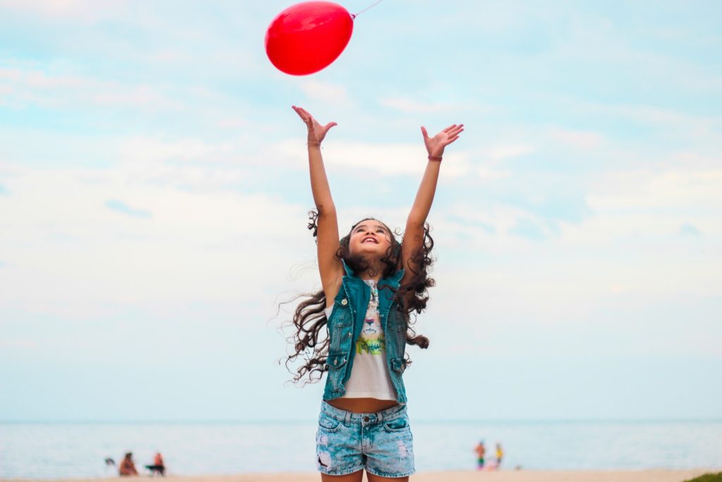 Girl throwing red balloon in air