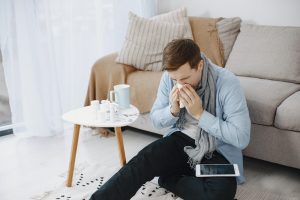man with seasonal allergies sneezing into tissue