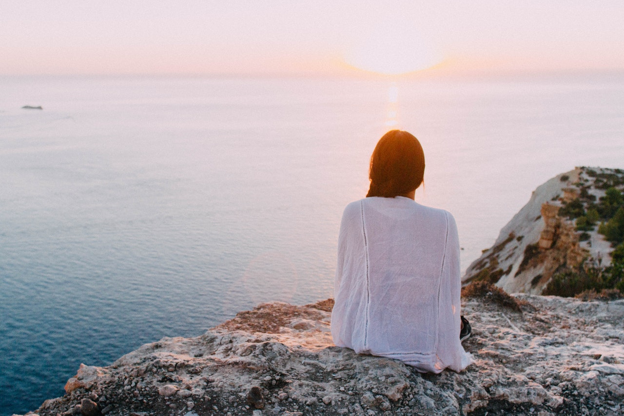 Woman sitting outside on cliff