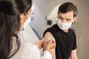doctor putting bandage on patient's arm after vaccine