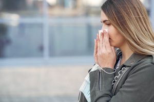 woman with seasonal allergies wiping nose