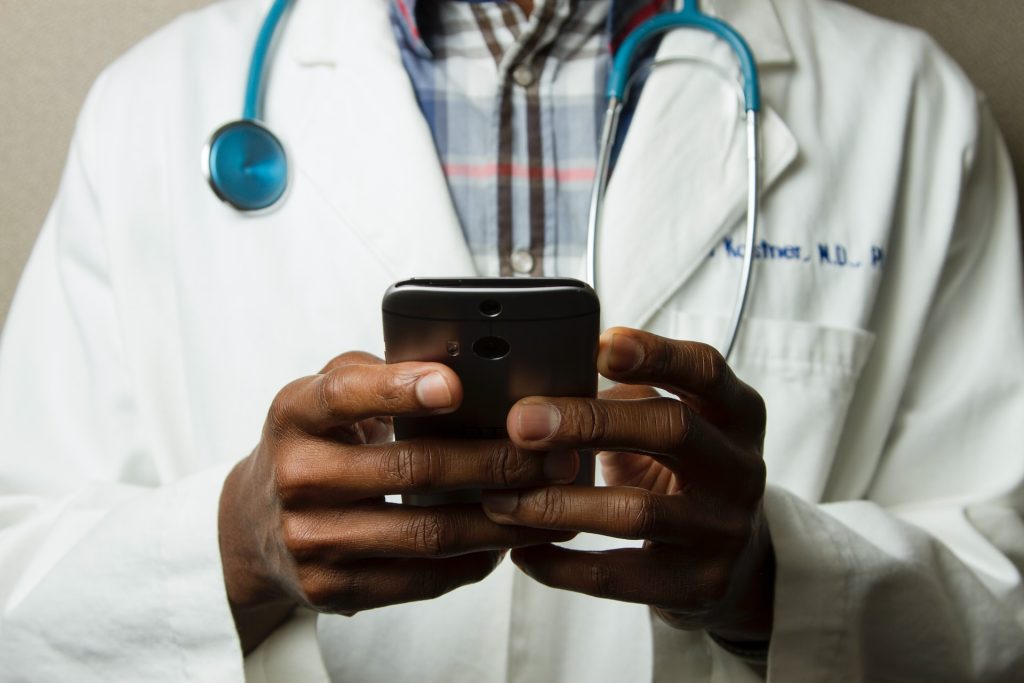 Doctor taking notes on phone during telehealth appointment