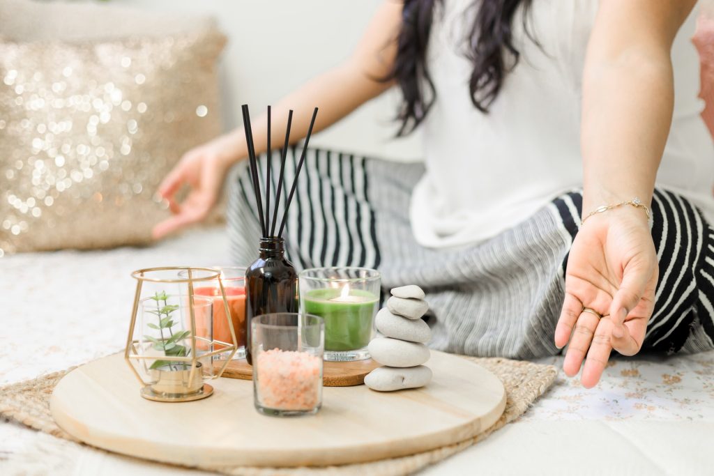 A woman practicing meditation with stones and candles