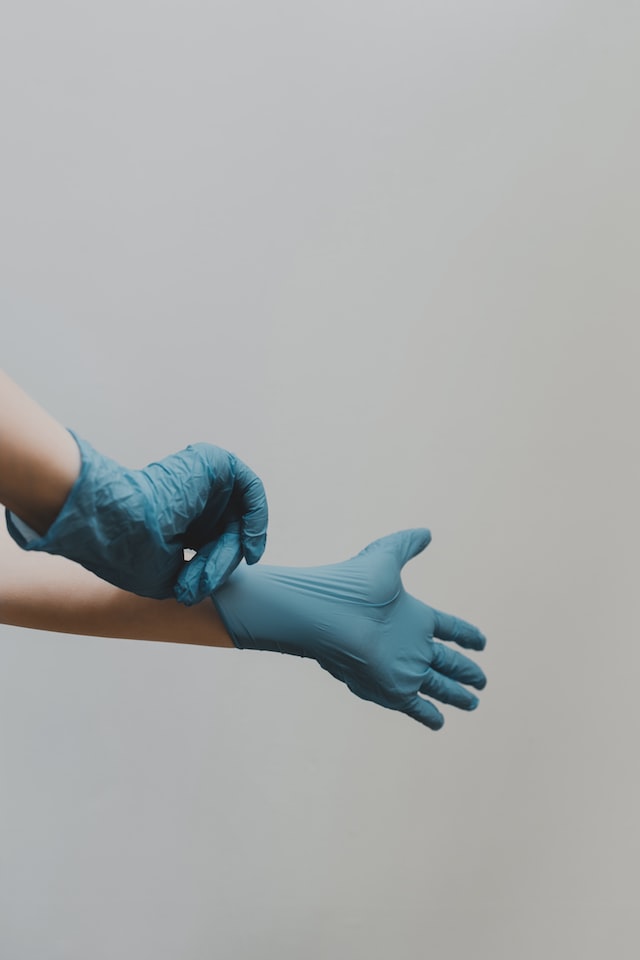 doctor putting on blue rubber gloves