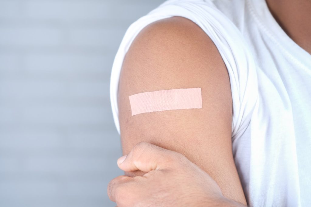 person wearing bandage on arm after vaccine